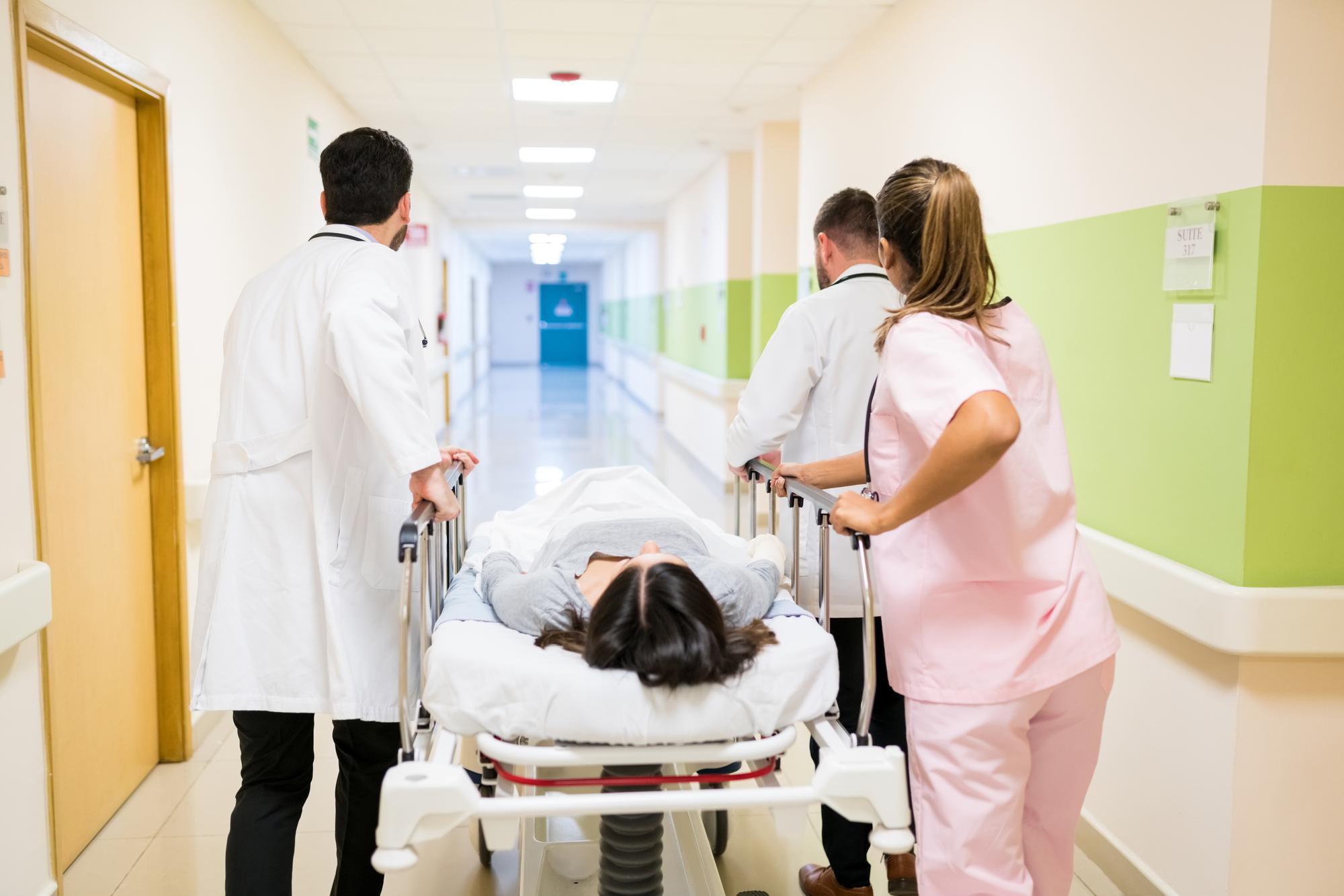 doctors-nurse-pushing-female-patient-stretcher-corridor-hospital